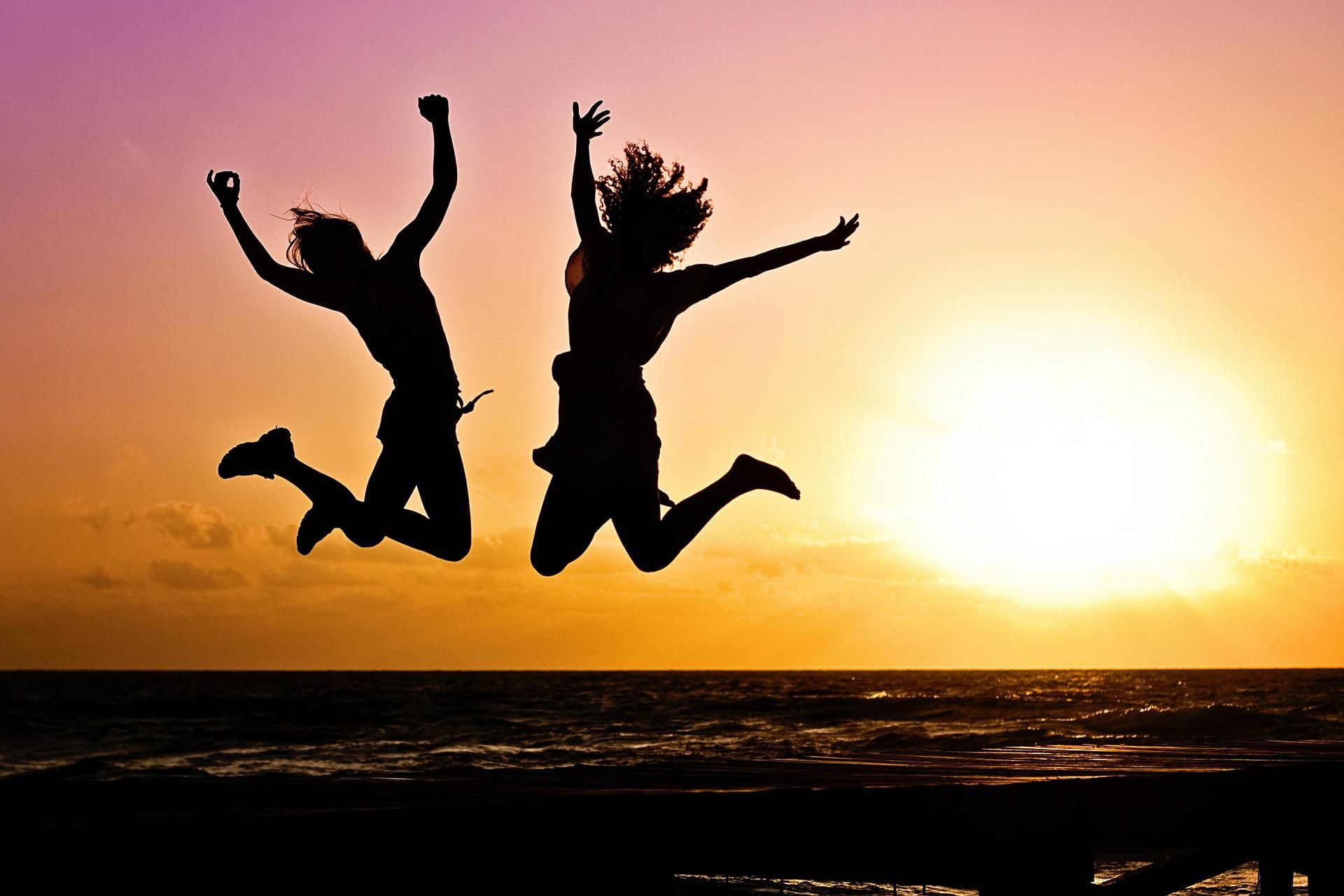 Zwei Menschen springen bei Sonnenuntergang in die Luft