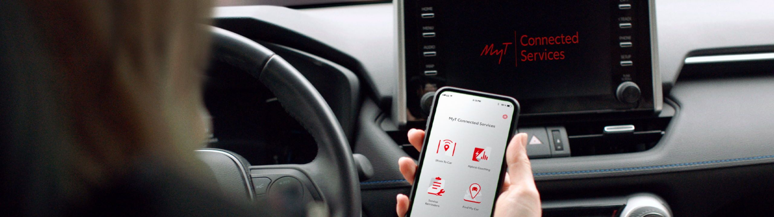 Fahrer im Cockpit eines Toyota schaut auf sein Smartphone mit geöffneter Toyota MyT-App